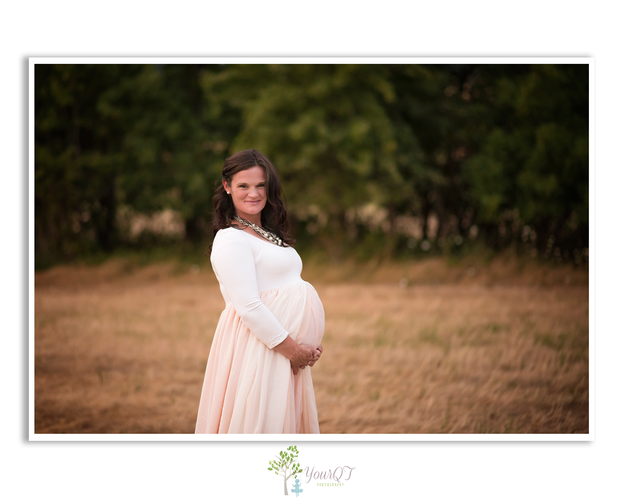 Carrie Maternity Portland Oregon Pink Blush Dress smiling in a field