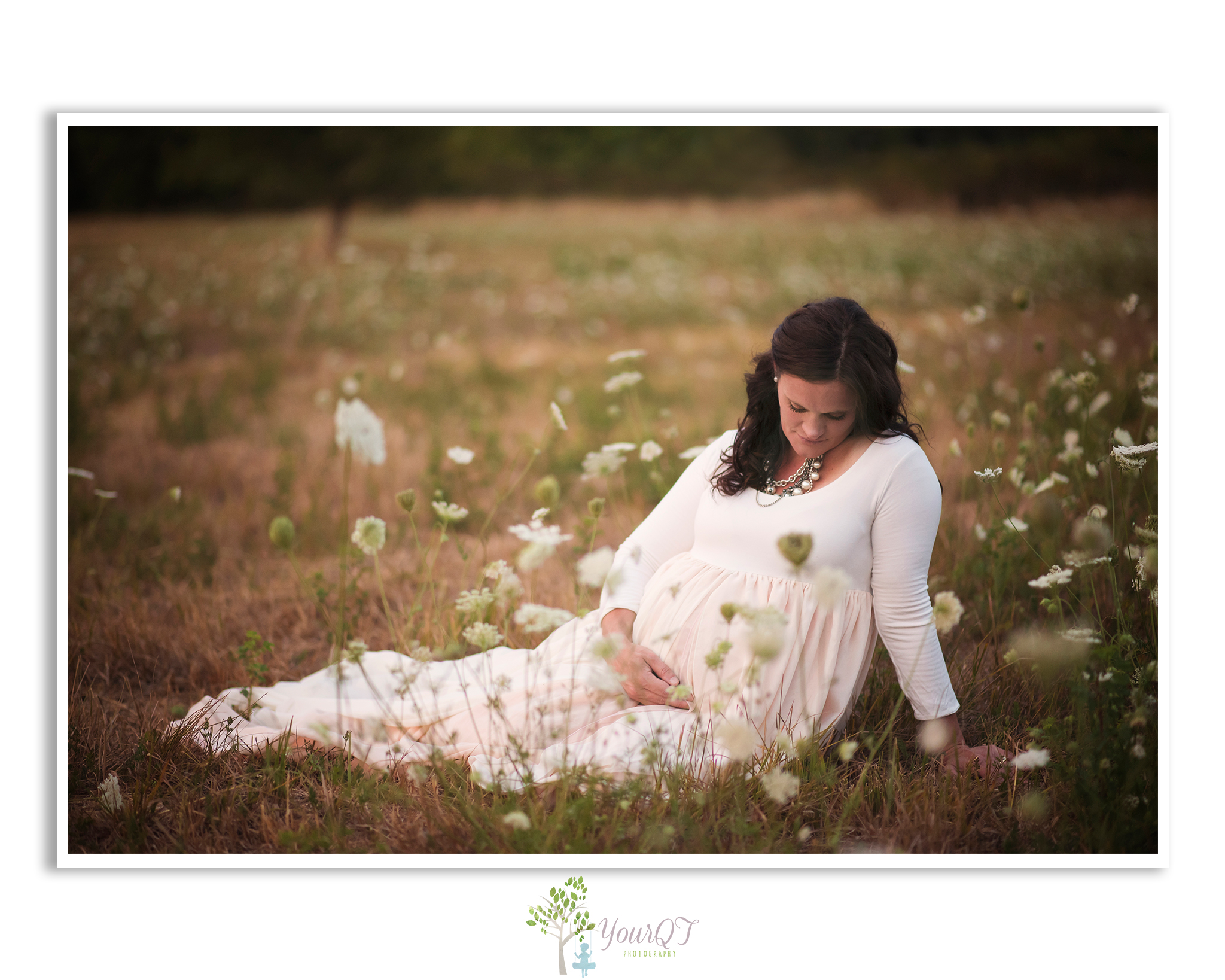 Carrie Maternity Portland Oregon Pink Blush Dress looking down in a field of flowers