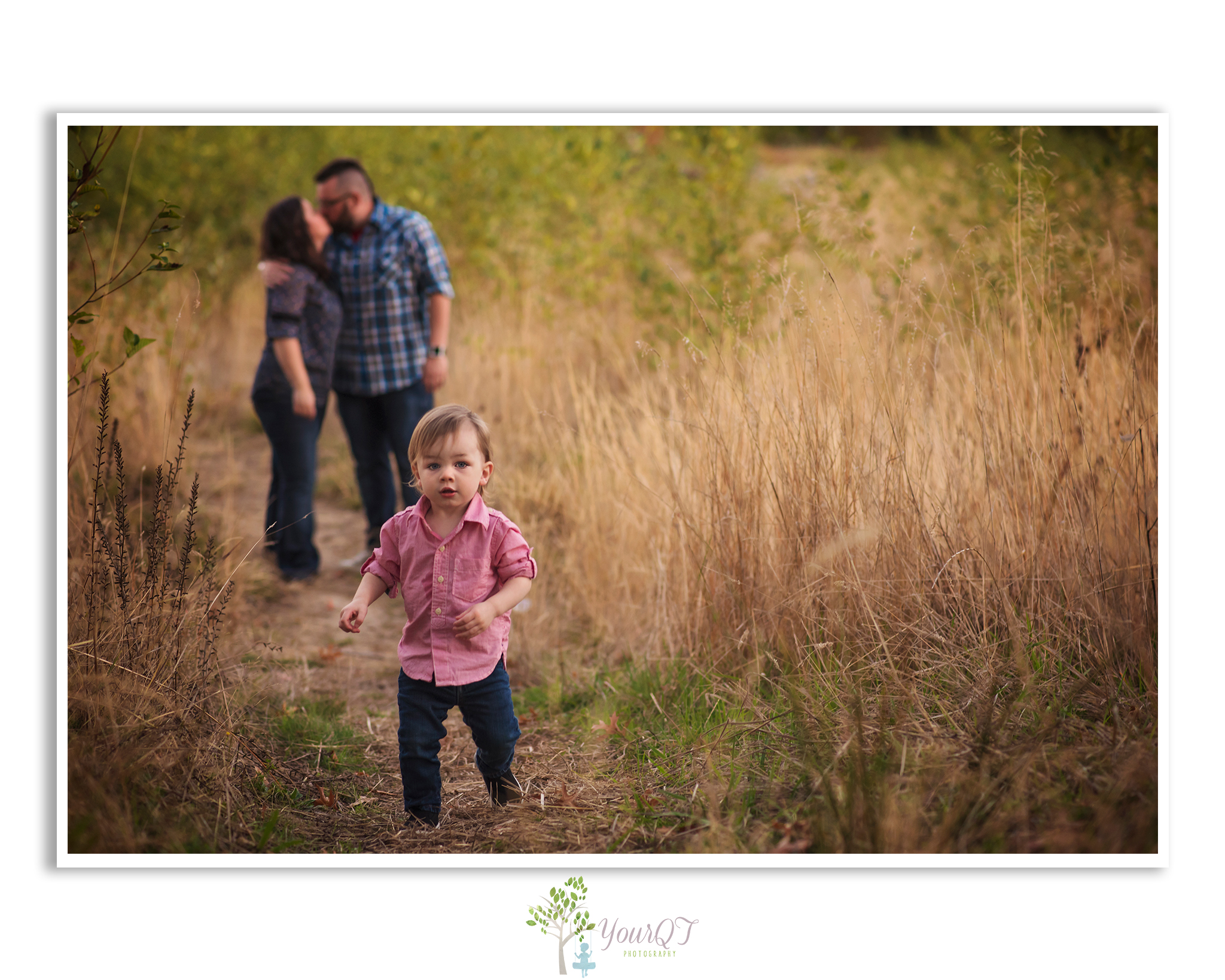 Schultz Family Preview husband and wife kissing in a field while boy is running towards camera